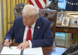 President Donald Trump signs a bill in to law sitting in the White House.